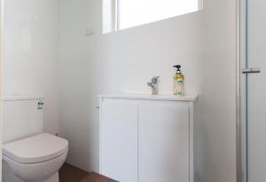 a white bathroom with a toilet and a sink at St Kilda absolute beachfront views in Melbourne