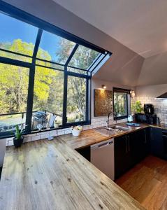 a kitchen with large windows and a wooden floor at Sun Views Forest yet close to town in Queenstown