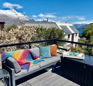 a couch on a balcony with a view of mountains at Sun Views Forest yet close to town in Queenstown