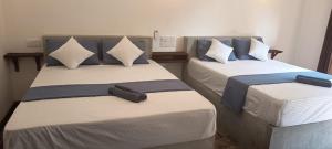 two beds with blue and white pillows in a room at Loveena by H.S. Restaurant & Guest in Tangalle