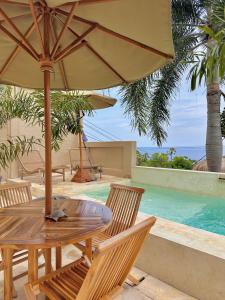 a wooden table with an umbrella next to a swimming pool at Jepun Hill Studios & Amed Jepun Divers in Amed