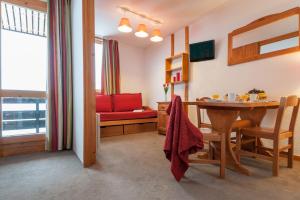 ein Esszimmer mit einem Tisch und einem roten Sofa in der Unterkunft Quartier Crève Cœur - maeva Home in Valmorel