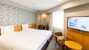 a hotel room with a bed and a flat screen tv at Richmond Hotel Sapporo Ekimae in Sapporo