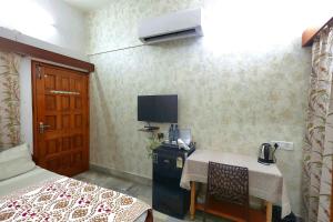 a room with a bed and a table and a television at Matrika Rooms in Lucknow