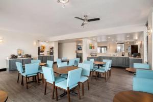 a dining room with blue chairs and tables and a kitchen at Quality Inn Foley - Gulf Shores North in Foley