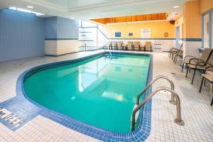 a pool in a hotel room with chairs and tables at Comfort Hotel & Suites in Peterborough