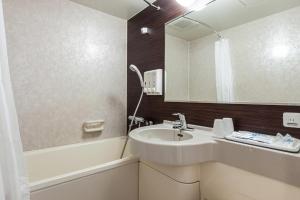 a bathroom with a sink and a tub and a mirror at Comfort Hotel Shin Yamaguchi in Yamaguchi