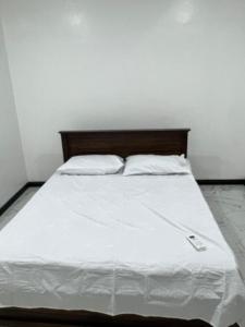 a bed with white sheets and a wooden headboard at Aathi Villas in Jaffna