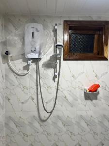 a shower in a bathroom with white marble walls at Aathi Villas in Jaffna