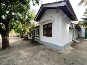 a white house with a tree next to it at Aathi Villas in Jaffna
