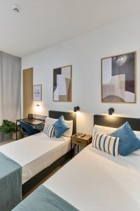 two beds in a hotel room with blue pillows at Sant Adrià Urban Suites by gaiarooms in Badalona