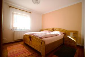 a bedroom with a wooden bed and a window at Almhaus Karantanien in Hochrindl