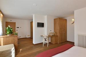 a bedroom with a bed and a desk and a television at Hotel Beau Sejour in Etroubles