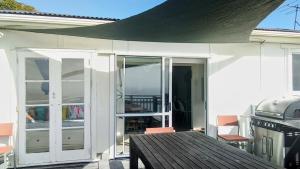 an open patio door with a table and a grill at Ahu in Piha