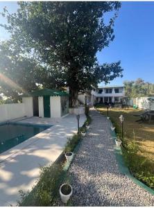 a pathway leading to a house with a tree at The Jungle Castle Resort in Rāmnagar