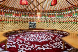a round bed in a yurt with a red and white rug at Komay Yurt Camp Karakol in Karakol