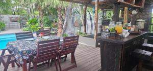 a table and chairs on a deck with a table and a pool at Rose Stable Cottage in Pretoria