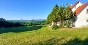 an image of a house with a tree next to it at Royal Panoráma Vendégház in Pécsely