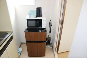 a microwave oven sitting on top of a wooden stand at Joinus Ise Apartment by Tranova in Ise