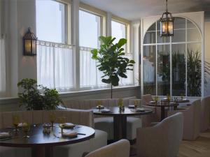 a dining room with tables and chairs and windows at The Bellevue Hotel, in the Unbound Collection by Hyatt in Philadelphia