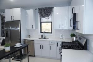 a kitchen with white cabinets and a sink and a refrigerator at Big apple room 33 in West New York +10 photos