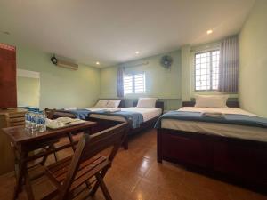 a room with three beds and a table and chairs at Kim Long Hotel in Can Tho