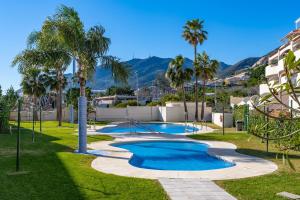 a swimming pool with palm trees in a park at Vistolmar Tivoli A213 in Benalmádena