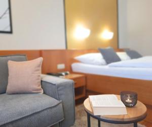 a hotel room with a couch and a table with a book at Appartementhaus Gaby in Bad Füssing