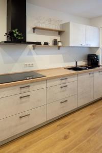 a kitchen with white cabinets and a wooden floor at Heimbi Home No 2 I 4-5 Personen I Familienfreundlich I Balkon I Nähe EuropaPark I Parkplatz I E Ladestation in Schwanau