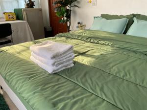 a pile of towels sitting on top of a bed at พี เจ เอ็ม โฮมสเตย์ in Ban Nong Chaeng