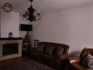 a living room with two leather couches and a chandelier at Melodia do Campo in Terras de Bouro