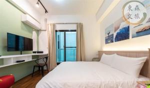 a bedroom with a bed and a desk with a television at 象日葵民宿-寵物友善-無門禁24小時進出-免費停車-東森文旅-包棟優惠中 in Wujie
