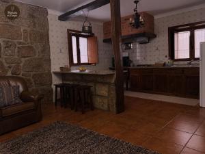 a kitchen with a stone wall and a table and chairs at Melodia do Campo in Terras de Bouro