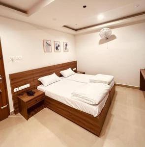 a bedroom with a large bed with white sheets at MALAPPURAM RESIDENCY in Malappuram