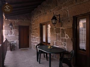 a table and chairs in a room with a stone wall at Refúgio da Geira in Campo do Gerês