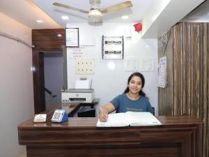 a woman sitting at a desk with a book at Shree Residency in Airoli