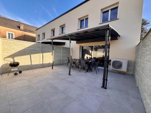 a patio with a table and chairs under a roof at maison 24 couchages in Clermont-Créans