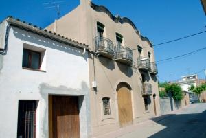 - un bâtiment blanc avec une porte en bois dans une rue dans l'établissement Ca la Paula, à Pla del Panadés
