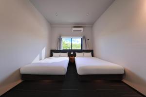 two beds in a small room with a window at クリスタルヴィラ大浦 in Miyako-jima +9 photos