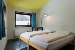 two beds in a room with a window at Zermatt Youth Hostel in Zermatt
