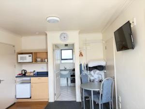 a kitchen with a table and a clock on a wall at Abode Motel in Palmerston North +11 photos