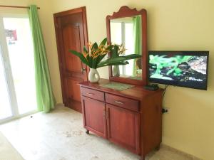 a dresser with a mirror and a television on it at Las Galeras Hotel in Las Galeras