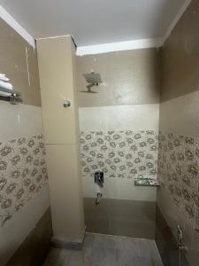 a bathroom with a shower with a tiled wall at Hotel KS GRAND in Mandhana