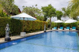 a swimming pool with chairs and umbrellas in a resort at Cove Jiwana Villa in Nusa Dua