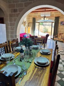 a wooden table with plates and glasses on it at Ta Carmen Farmhouse with pool in Qala