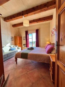 a bedroom with a bed and a couch in a room at Ta Carmen Farmhouse with pool in Qala