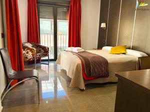 a bedroom with a bed with red curtains and a chair at HS Alcalá in Alcalá del Júcar