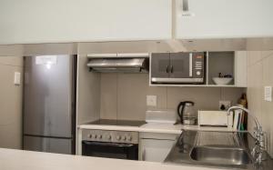 a kitchen with a sink and a stainless steel refrigerator at 802 The Bermudas - by Stay in Umhlanga in Durban