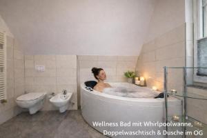 a woman sitting in a bath tub in a bathroom at Villa Mara - für 12 Gäste, Sauna, 1 Wirlwanne, 2 Duschen, Kamin, 5 SZ, 3 WC, Highspeed Internet, abgezeuntes Grundstück in Glowe +17 photos