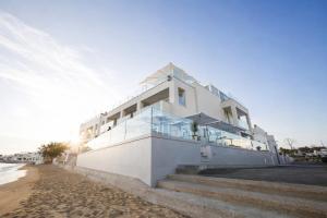 a white house on the beach with stairs at Hotiday Torre Pali Spiaggia in Torre Pali